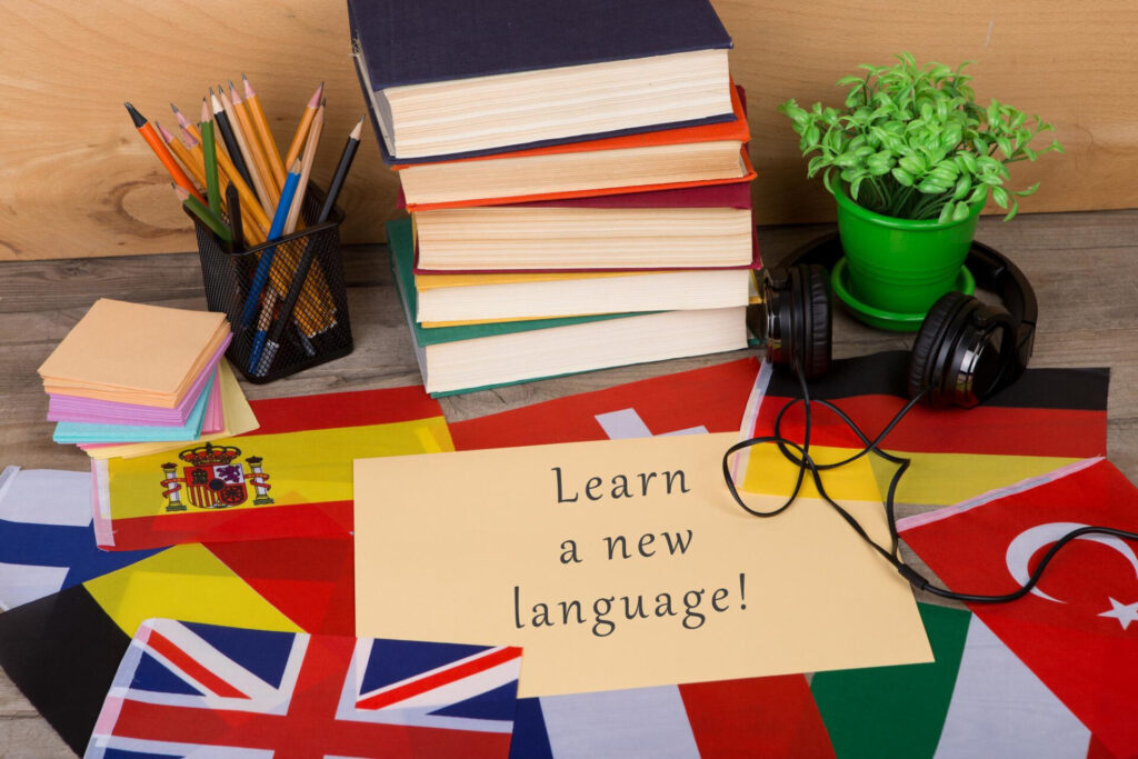 a stack of books and headphones on a table - language learning hacks