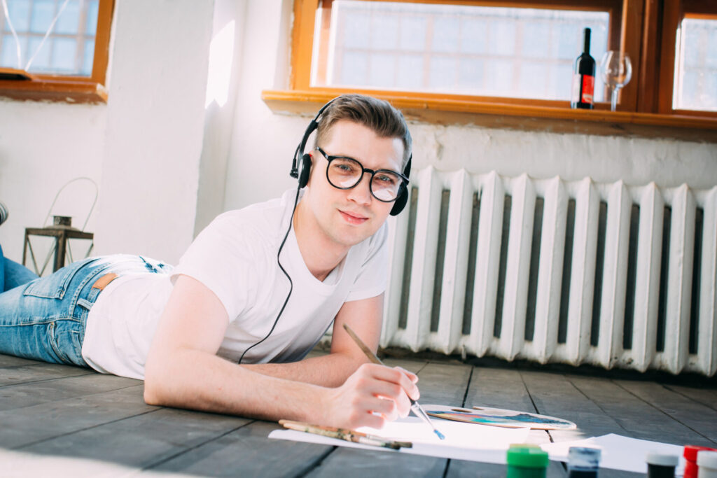 a teenage boy wearing glasses and headphones drawing on paper