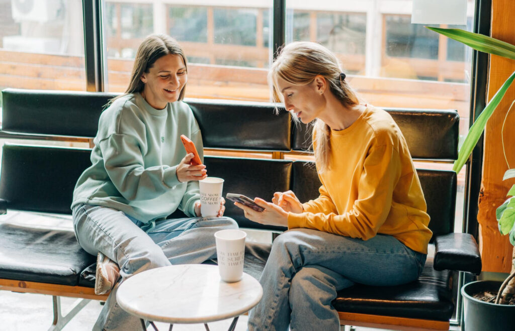 how to make small talk: two women sitting on a bench looking at their phones
