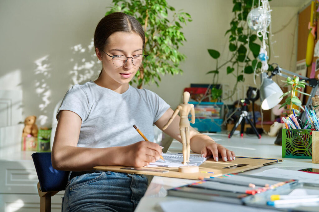 a girl sitting at a table writing on a piece of paper