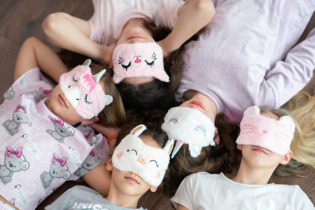 a group of girls lying down with masks on their eyes - bedtime routine for kids