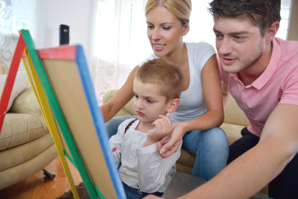 a man and woman looking at a child on a easel