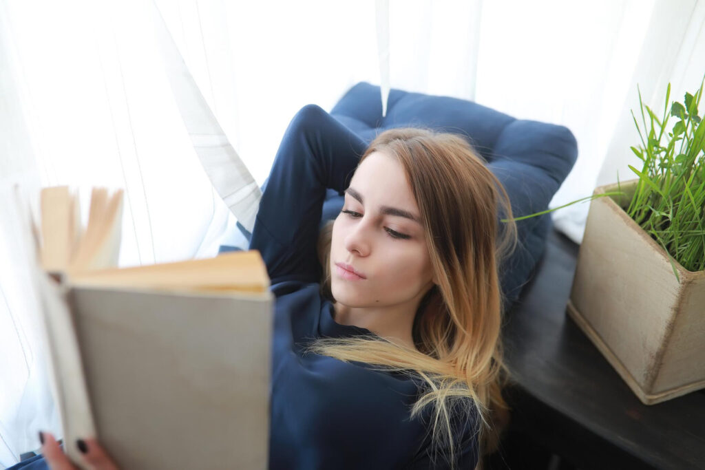 a woman lying on a chair reading a book - best speed reading techniques