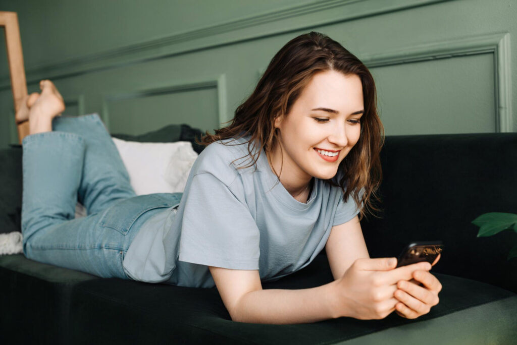 how to read between the lines in a text: a woman lying on a couch looking at a phone