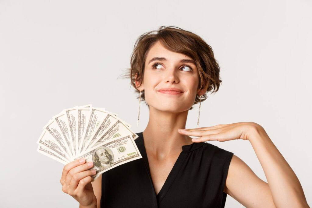 a woman holding a fan of money - budgeting for beginners