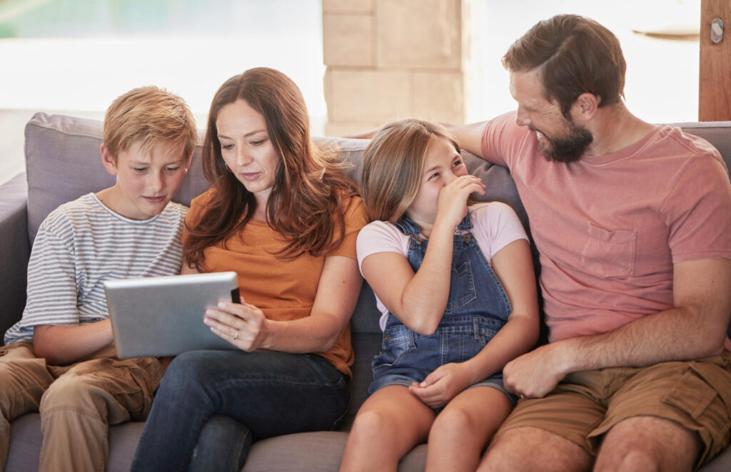 a family sitting on a couch looking at a tablet - building respect in blended families