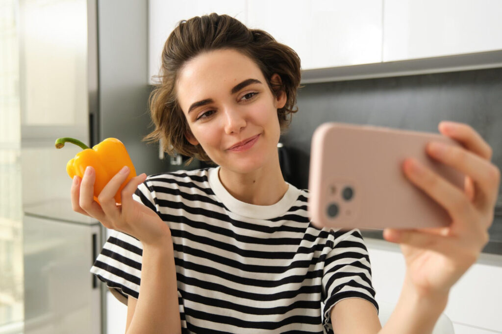 a woman holding a pepper and a cell phone