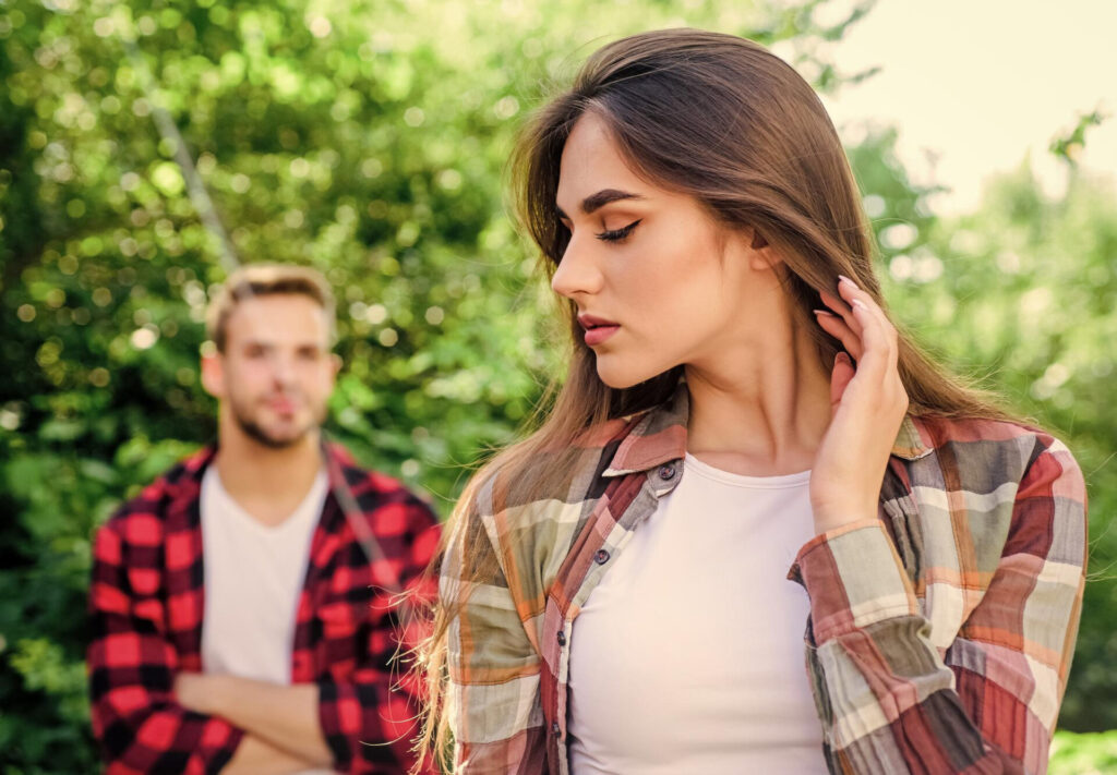 a woman with her hand on her neck and a man in the background