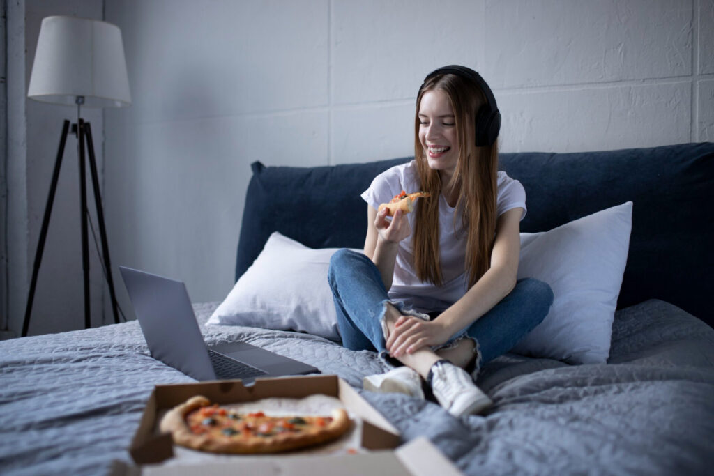 best ways to set personal boundaries for alone time: a woman sitting on a bed eating pizza