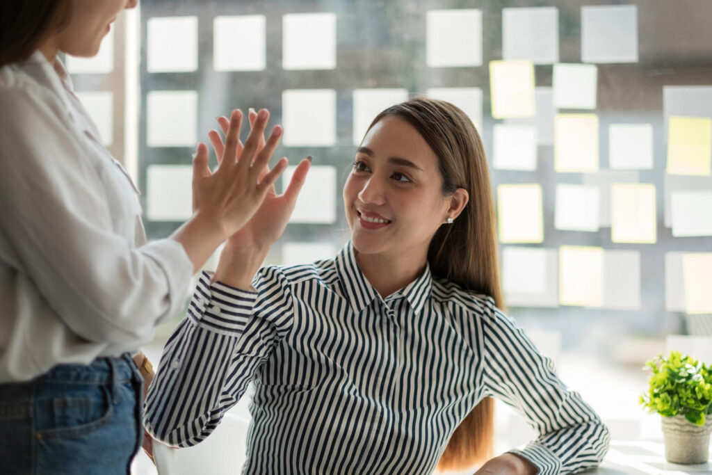 how to give constructive feedback: a woman giving a high five to a man