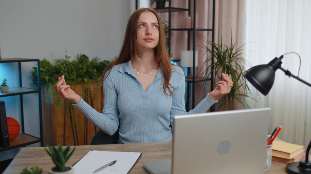 a woman sitting at a desk with her hands up