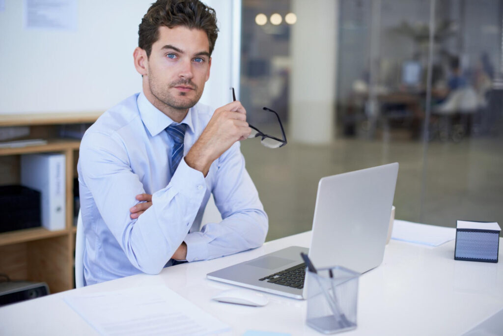 a man sitting at a desk with a laptop and glasses - rewire your brain for success