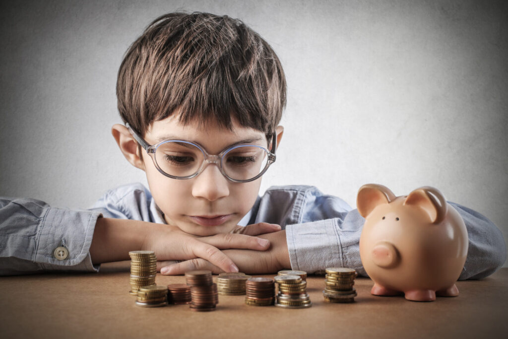 a boy looking at a piggy bank - money management for kids