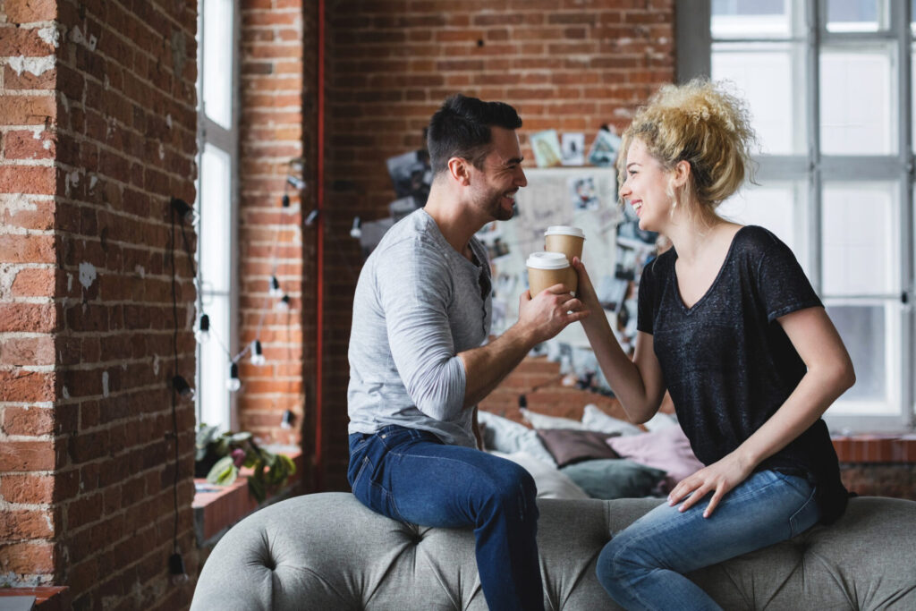 a man and woman sitting on a couch holding coffee cups