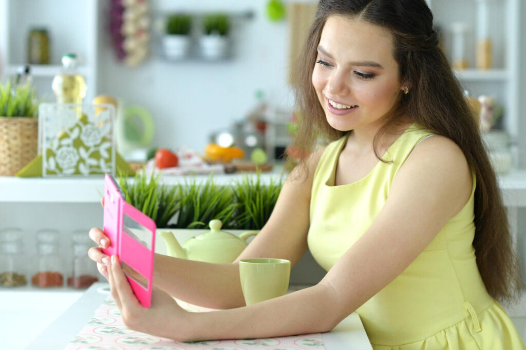 a woman sitting at a table looking at a pink mirror