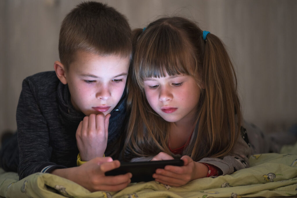 a boy and girl looking at a phone - screen time recommendations for kids