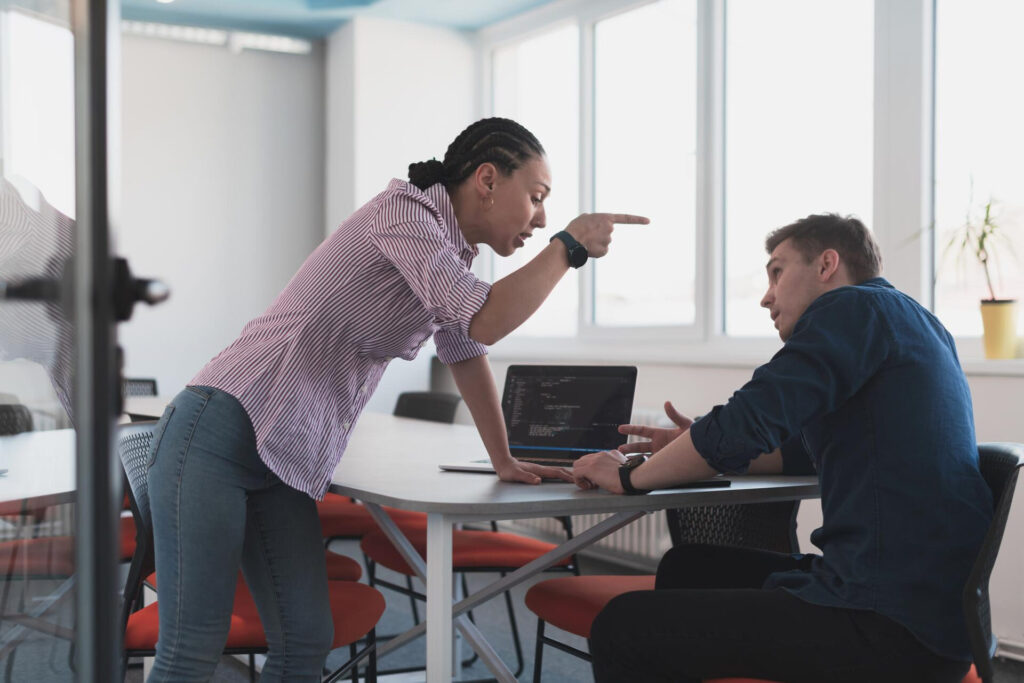 how to handle conflict at work: a woman pointing at a man at a table