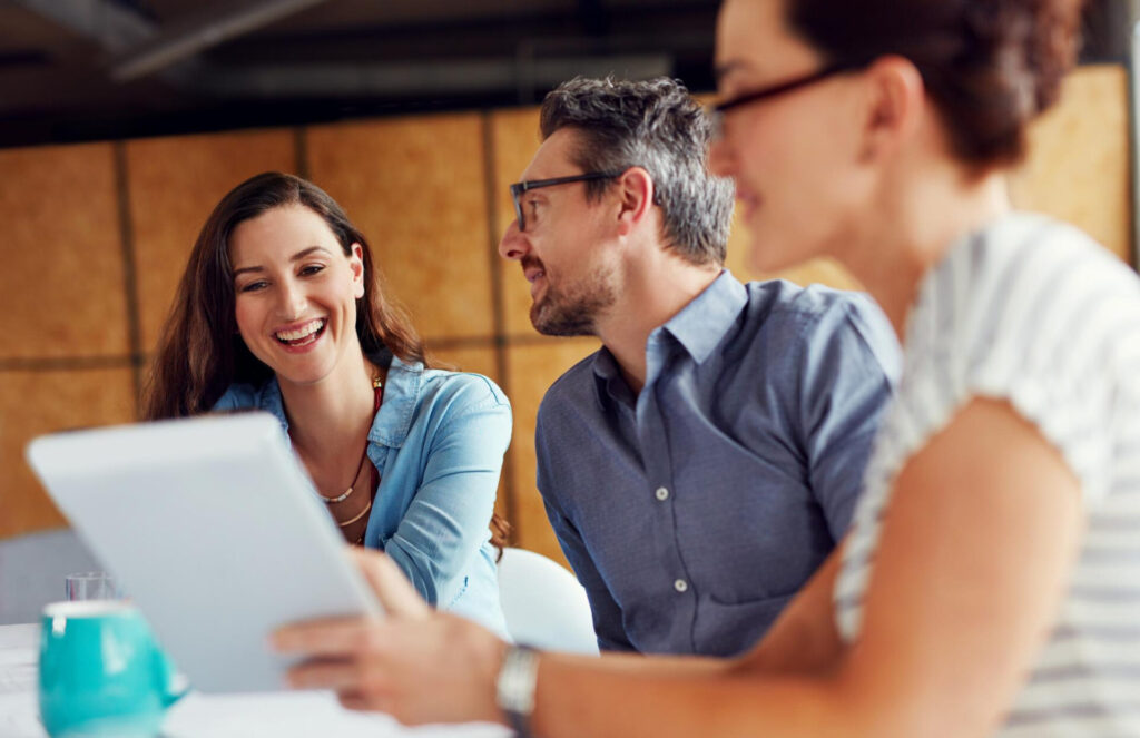 how to ask better questions: a group of people looking at a tablet