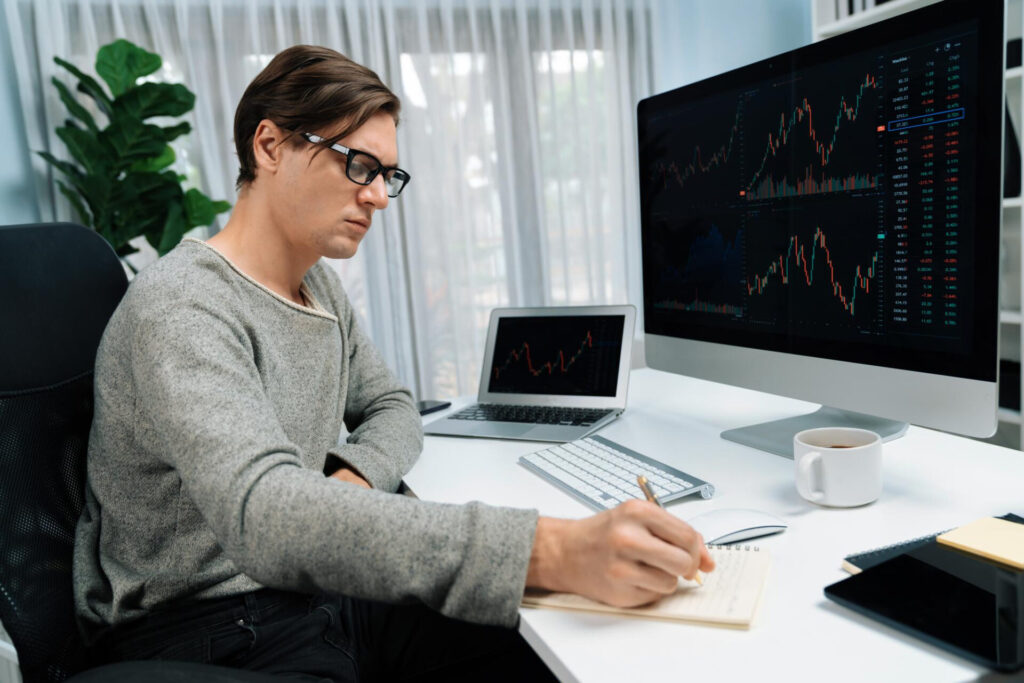 Investing - a man sitting at a desk writing on a notebook