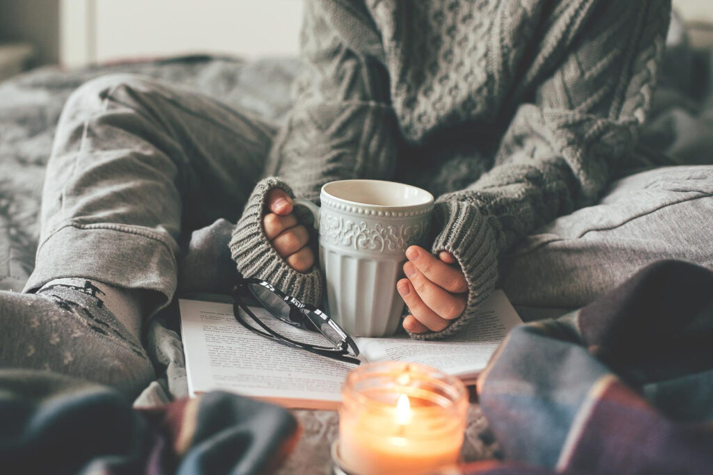 a person holding a cup and reading a book