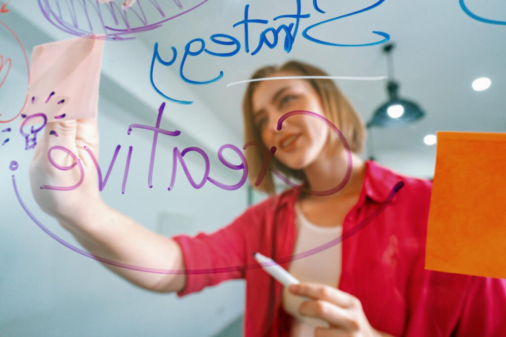 a woman writing on a glass board - best study techniques