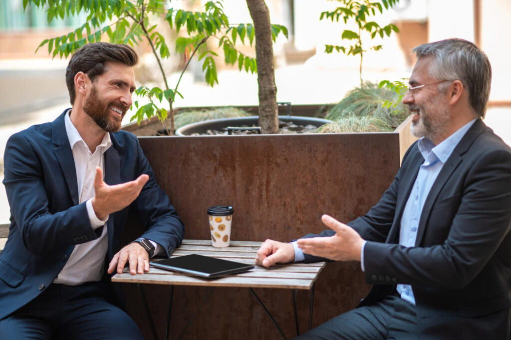 mirroring body language in sales: two men sitting at a table talking