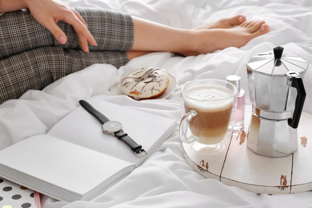 a person sitting on a bed with a donut and a book