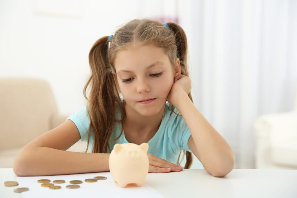 a girl looking at a piggy bank
