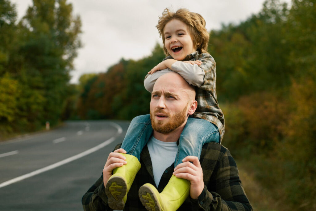 a man carrying a child on his shoulders - best single parent survival guide