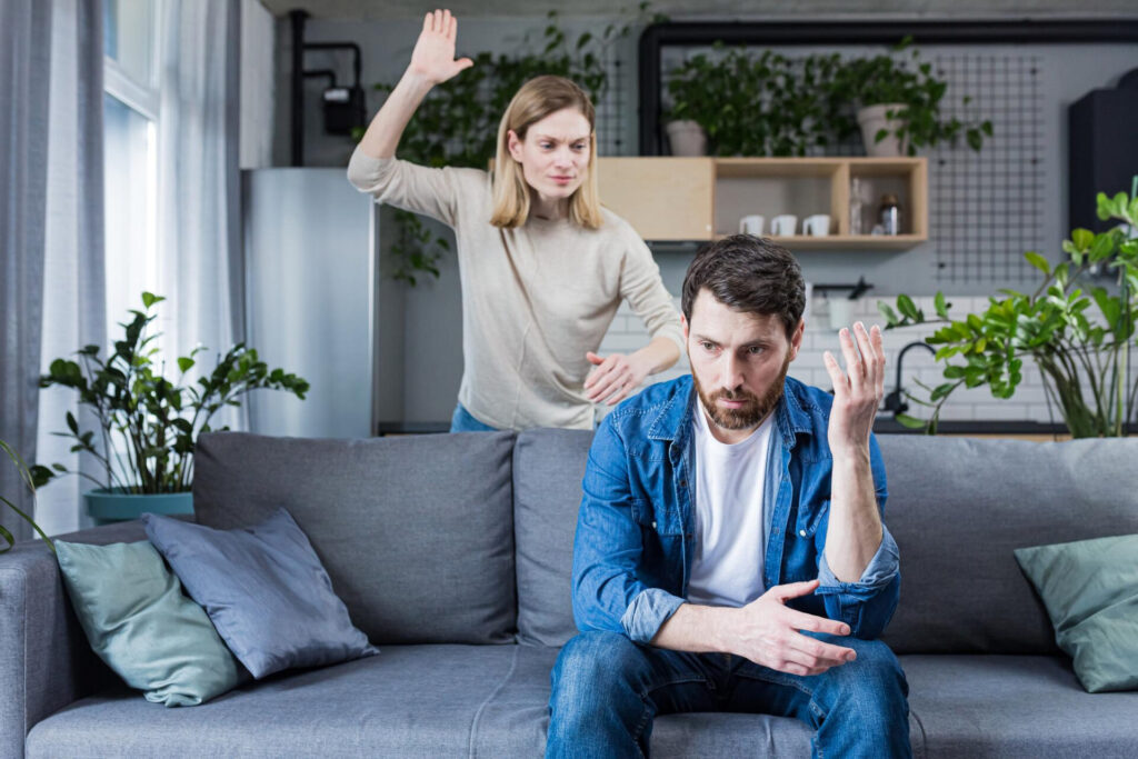 a man sitting on a couch with a woman standing behind him