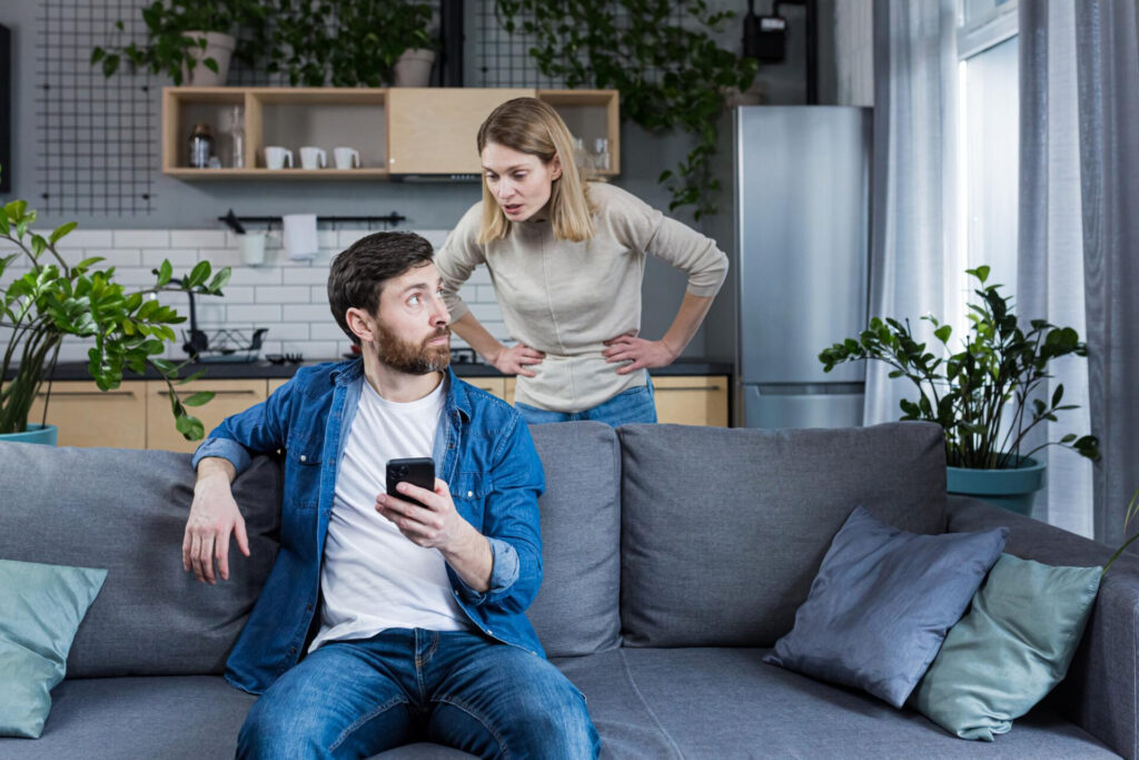 a man sitting on a couch with a woman behind him